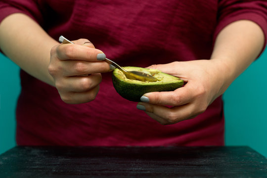 Woman Use A Spoon To Scoop The Avocado Out Of The Shell