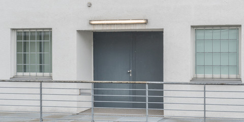 Graue Tür einer Lagerhalle mit gesicherten Fenstern