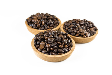 Preparing fresh roasted coffee beans in small wooden bowl on white background.