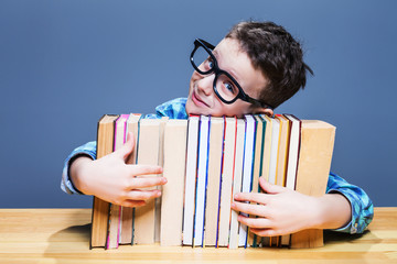 Pupil in glasses hugs books, education concept