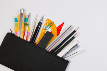 Student pencil bag or pencil case with school supplies for student. Black pencil box with school equipment isolated on white background. Top view