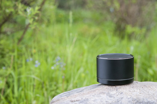 Bluetooth speaker standing on a big stone over nature background. © gangster9686