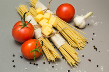 A set of ingredients for cooking pasta on a gray background