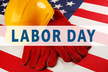 Fototapeta na wymiar Labor day concept. Yellow helmet and gloves on USA national flag background