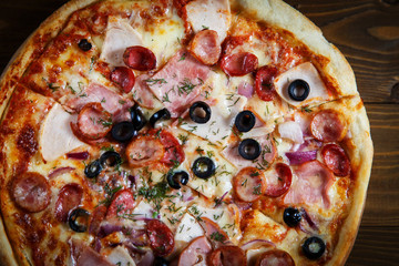 Delicious homemade pizza with mozzarella, ham, olives and fennel.