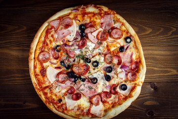 Delicious homemade pizza with mozzarella, ham, olives and fennel.