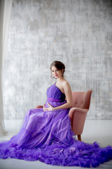 beautiful pregnant woman posing in purple dress in Studio