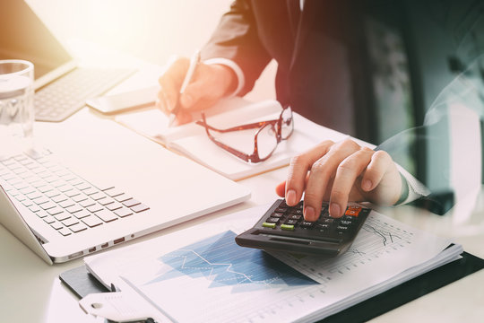 businessman hand working with finances about cost and calculator and latop with mobile phone on withe desk in modern office