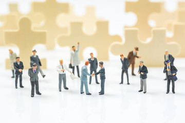 business miniature people shaking hands with jigsaw puzzle piece field background