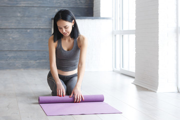 Fototapeta premium Young yoga Woman rolling her lilac mat