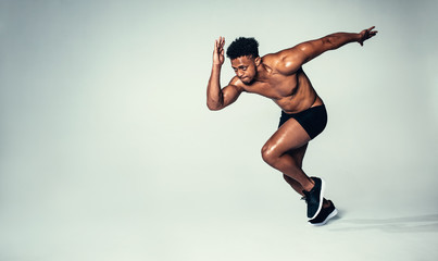 Fit young man running over grey background