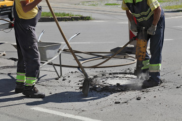 Worker at construction site demolishing asphalt with pneumatic jackhammer