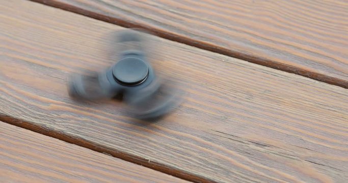 A high speed spinning hand spinner or fidget spinner over the wooden background.