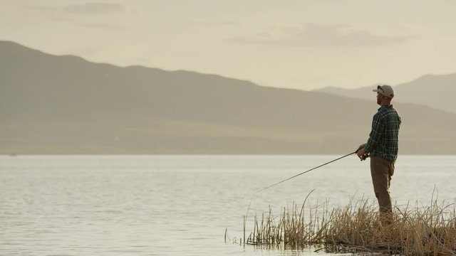 Wide Panning Shot Of Man Fly Fishing At Lake. Vineyard, Utah, United States