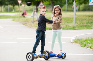 little boy and girl riding on the hoverboard in the park