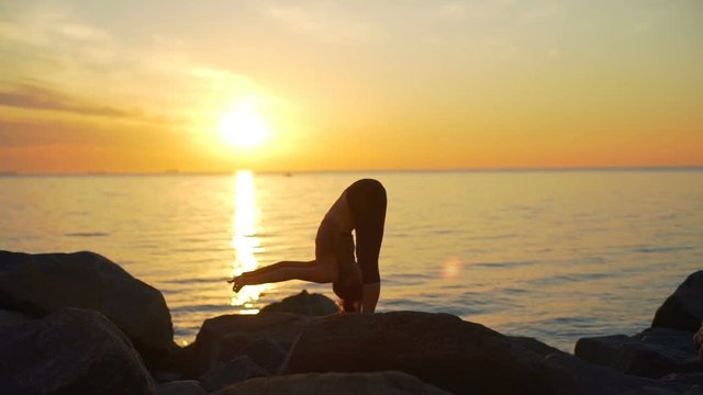 Healthy young beautiful woman practicing yoga ocean coast sundawn slow motion