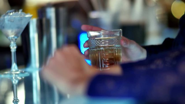 Hand holding a glass of whiskey in bar