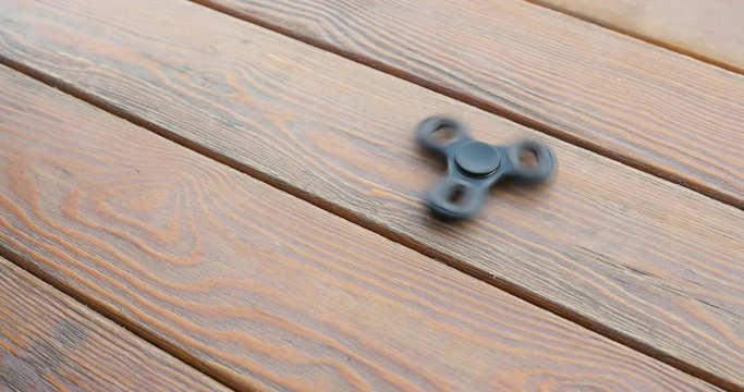 hand spinner, or fidgeting spinner, rotating on the floor. wooden background.