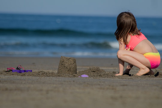A young girl is building with sand at the beach (Series 3)