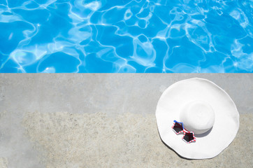 Fototapeta na wymiar Summer background with hat and sunglasses near the pool