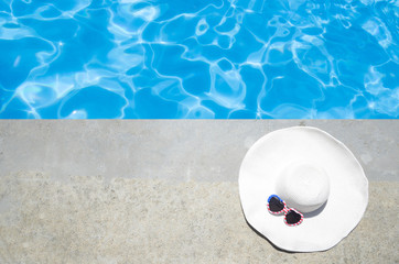 Fototapeta na wymiar Summer background with hat and sunglasses near the pool