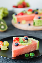 Watermelon pizza slice with fruits, dark background