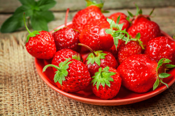Strawberries in bowl on rustic table.