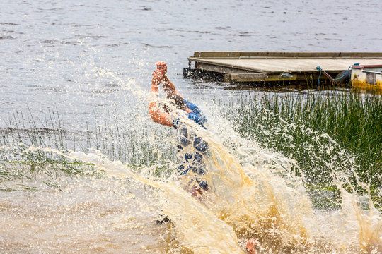 Man splashing in muddy water after riding a natural water slide.