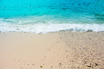 Oceanic view with sand beach and sea wave. Turquoise blue tropical sea lagoon for perfect vacation.