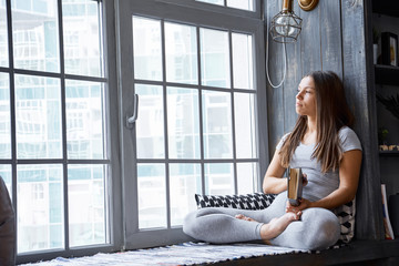 Woman reading book at home in the living room.