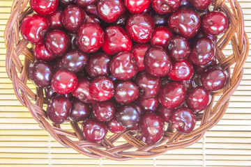 Fresh cherries in a plate on a bamboo table