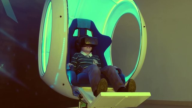 Little boy enjoying virtual reality in a moving interactive chair