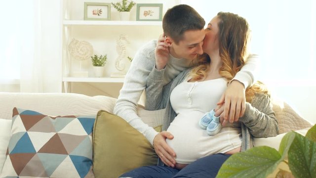 Happy young couple expecting baby. Beautiful pregnant woman and her husband together caressing her pregnant belly. 4K UHD video 3840X2160