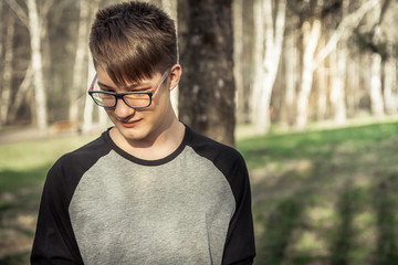 Shy teenager hipster boy in eyeglasses outdoors