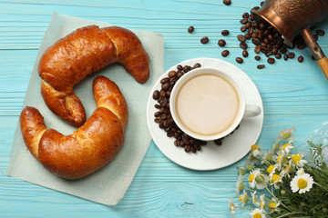 Coffee background. Cup of coffee with croissant and coffee beans on blue wooden background. Top view