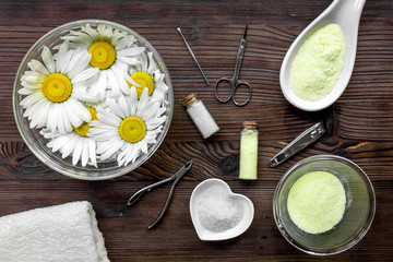 Manicure set with spa salt and chamomile on dark wooden desk top view