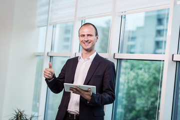 Fototapeta premium Close up image of business man holding a digital tablet,Portrait of handsome young man working with tablet in the office.Intelligent and confidents businessman holding touch pad with infographics