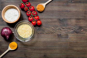paella ingredients with rice, salt, spices and tomatoes on wooden table background top view mockup