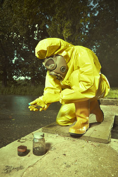 Man in chemical protective suit collecting samples of very bad water contamination