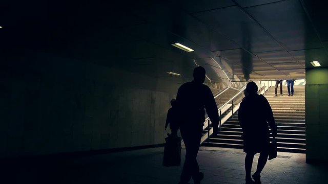 Silhouettes of people crossing the road. The woman slowly hobbling with a man.