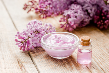 Fototapeta na wymiar organic cream, extract in lilac cosmetic set with flowers on wooden table background