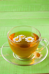 Herbal tea with fresh chamomile flowers on green wooden background with copy space for your text