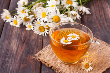 Obraz na płótnie Canvas Herbal tea with fresh chamomile flowers on black wooden background