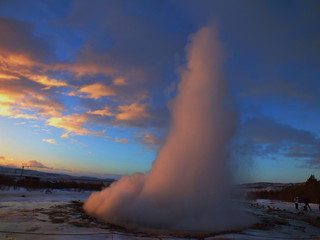 Shot of the ejection of the geyser Strokkur in Iceland during winter with a sunrise in the background.