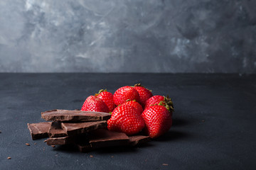 Strawberry with slices of chocolate on a dark background