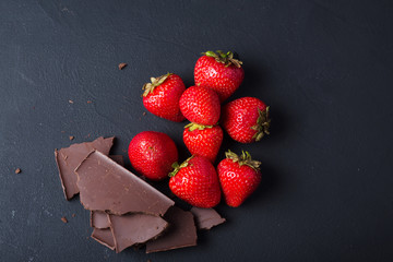 Strawberry with slices of chocolate on a dark background