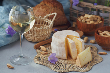 A head of fresh organic cheese served with bread, nuts, white wine and summer flowers.