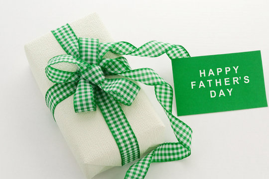 Happy Father's Day. Creamy Gift with a chequered ribbon on a white background. Greeting Card.