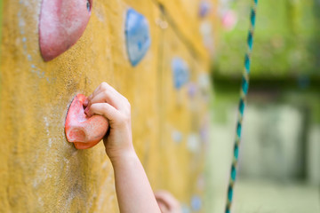 children's hand holds a stone on the rock climbing wall