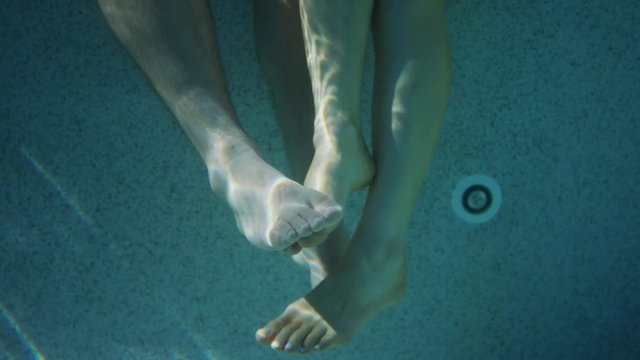 Close up shot of couple playing footsie underwater. Cedar Hills, Utah, United States